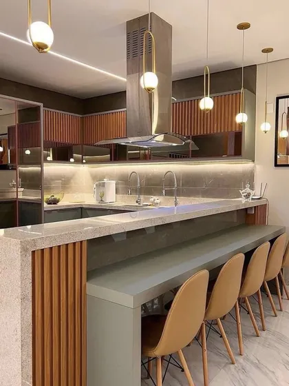 This kitchen features a long island with an extended breakfast counter that can seat up to four people. The fluted wood and grey color scheme is both modern and elegant.