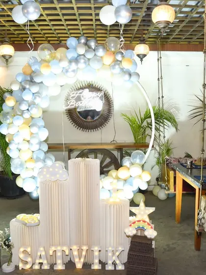 A wide view of a party setup with a blue, white, and yellow balloon arch and illuminated letters. We capture the overall ambiance and decor of your event space.