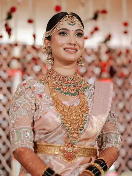 This bride is a vision in her pastel pink and peach saree. The custom blouse is heavily embroidered with floral motifs, creating a look of romantic elegance for her wedding day.