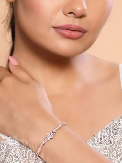 The focus is on the model's hand and wrist, displaying a sparkling bracelet against a sequined top, creating a glamorous look for party wear.