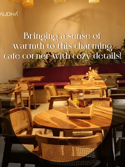 I love bringing warmth to a charming cafe corner. The combination of the purple upholstered bench, wooden tables, and rattan chairs, all framed by a backdrop of green plants, makes for a very cozy spot.