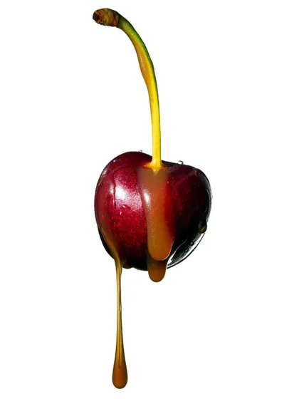 Another view of the cherry and caramel drip. This shot captures the drip as it elongates, showcasing the beauty of liquid in motion against a simple, clean backdrop.