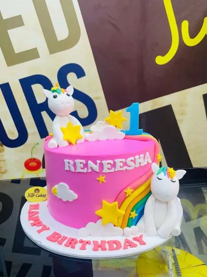 A dreamy 2kg unicorn cake with two fondant unicorns, a rainbow, and fluffy clouds.