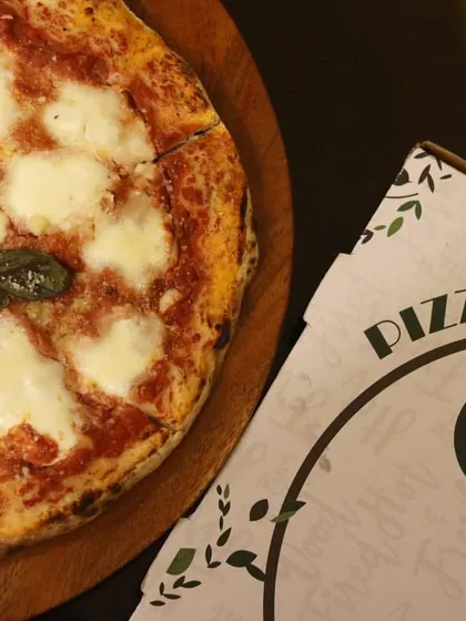 A classic Margherita pizza, sliced and ready to be served, next to one of my custom pizza boxes. Perfect for a cozy night in.