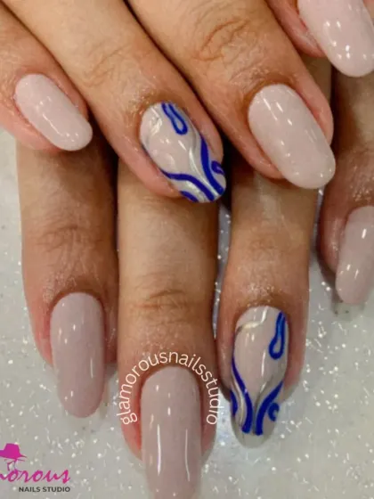 A modern and minimalist design with a pop of color. This set features clean, nude-colored nails with accent nails showcasing an abstract, wavy design in a bold royal blue and silver.