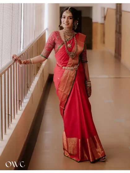 An elegant full-length portrait of the bride, showcasing her beautiful red saree and traditional jewellery.
