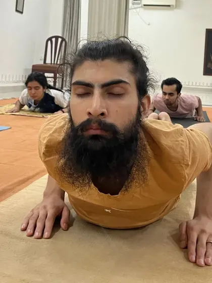 A participant holds Bhujangasana (cobra pose) with deep inward focus, strengthening his back and opening his heart.
