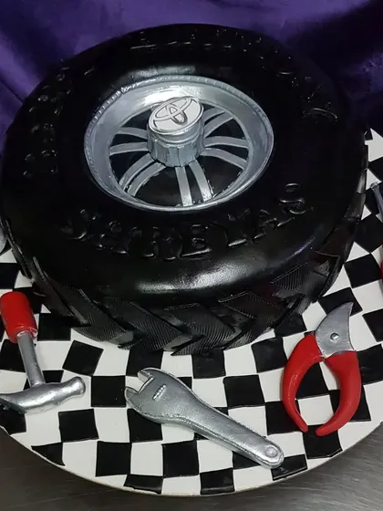 For the car enthusiast, this custom tyre cake comes with a set of edible tools on a checkered flag base. Every detail, from the tire treads to the wrench, is handcrafted to create a truly unique birthday cake.