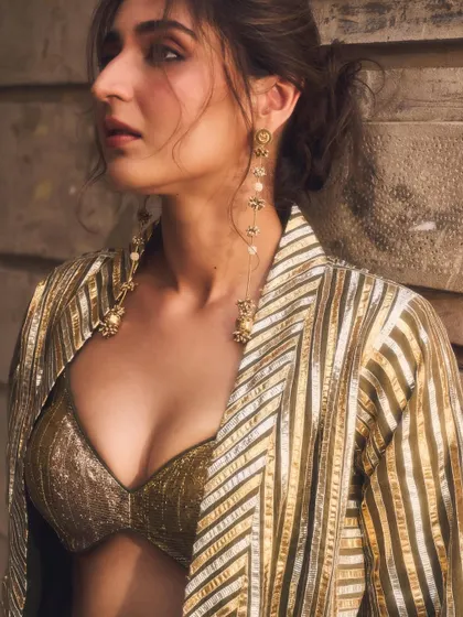 A close-up focusing on the hair and makeup that completes the look. The soft updo and long earrings frame the face beautifully.