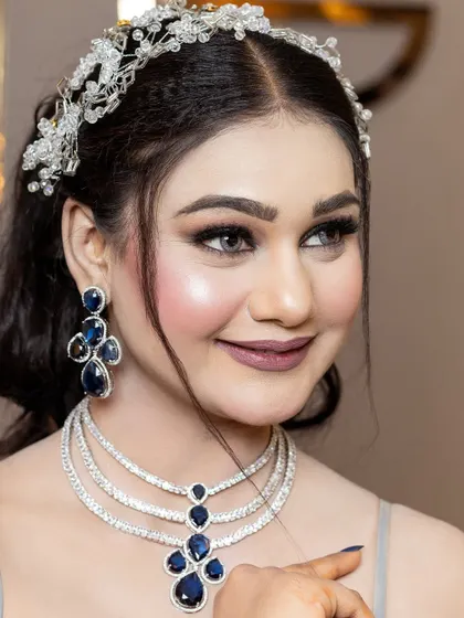A smiling portrait that captures the joy of the occasion. The makeup is designed to be radiant and photo-ready, with a focus on bright eyes and a flawless complexion.