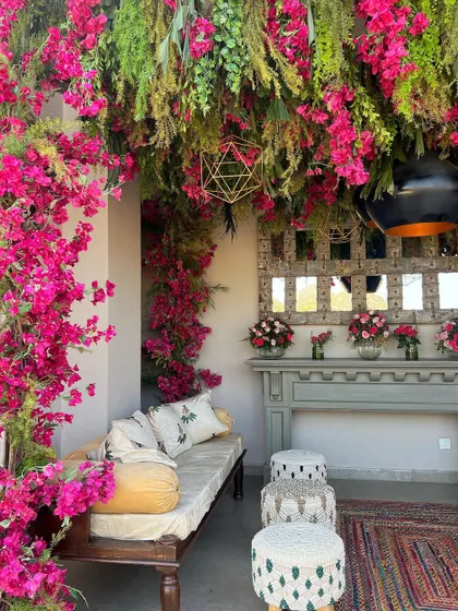 Another view of the curated corner, showcasing the blend of textures from the wooden furniture, woven stools, and lush florals.