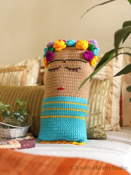 My Frida Kahlo inspired cushion, resting on a bed. I designed this piece to be a frank expression of creativity, adding a touch of art and personality to your most personal spaces.