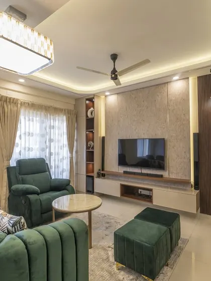 A view of the living room's entertainment zone. The TV unit features a textured back panel and dark wood accents, complemented by a modern ceiling light and comfortable recliner.