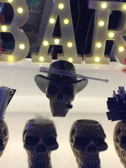 A fun and edgy shooter station with skull-shaped mugs and a light-up 'BAR' sign.