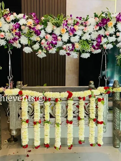 A beautiful silver cradle decorated with an arch of orchids and other exotic flowers. This modern and stylish floral arrangement is perfect for a contemporary naming ceremony.