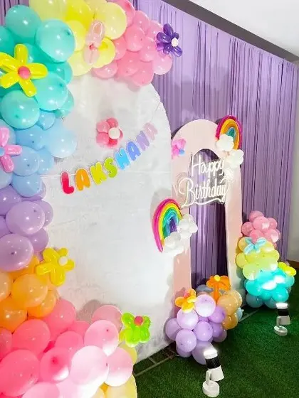This shot focuses on the organic balloon arch from the Rainbow theme party. It shows how different sized balloons and flower-shaped balloon accents are used to create texture and visual interest.