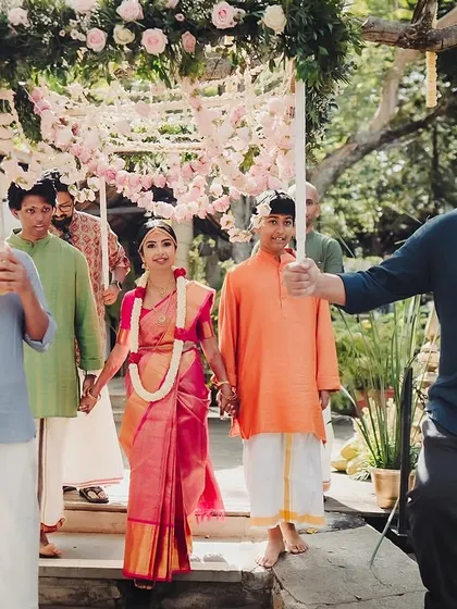The bride's processional, walking down the steps of the Kalyani under a floral canopy held by her loved ones.