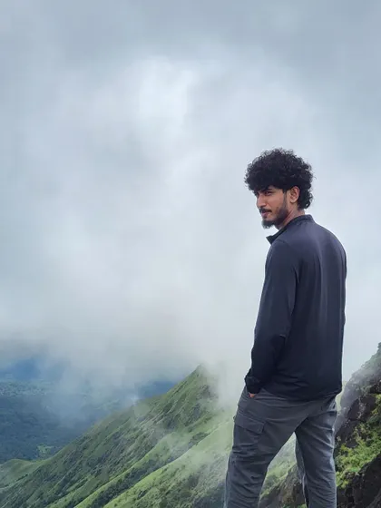 A trekker looking out at the misty valleys of Kumara Parvatha. The post-monsoon season offers clear views and pleasant weather.