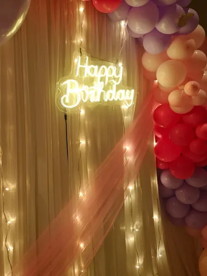 A close-up of the neon sign and balloon arch, showing how the lighting creates a warm, festive glow.