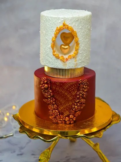 We are always learning and practicing new modern art techniques. This two-tier cake features a unique window design with a golden heart inside, and the bottom tier is decorated with intricate golden lace.