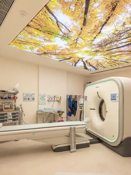 This CT scan room features a backlit ceiling panel with an image of a forest canopy. This biophilic element helps patients feel more connected to nature and less confined, playing a crucial role in their comfort during the procedure.