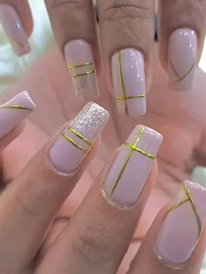 A sophisticated nude manicure with delicate gold line work and a sparkling glitter accent nail.
