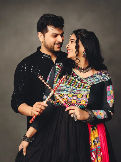 A loving glance during a Navratri-themed maternity shoot. The couple's colorful traditional outfits and dandiya sticks make for a unique and festive memory.