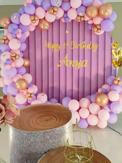 A chic butterfly-themed first birthday with a purple velvet backdrop, a pastel balloon arch, and gold butterfly accents.