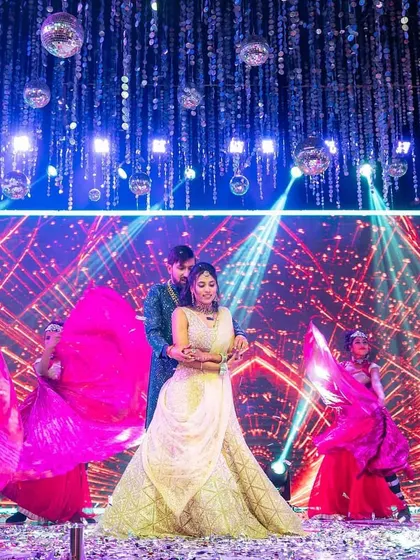 A grand sangeet performance with the couple at the center, surrounded by backup dancers and stunning lighting.