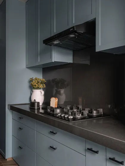 A detail of the kitchen, with its cool blue cabinetry and dark countertops, offering a sleek and modern workspace.