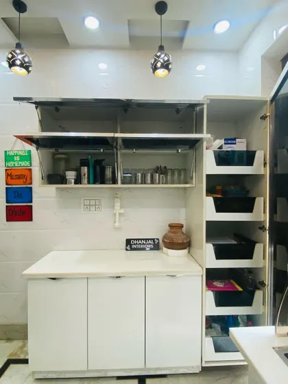 This compact kitchen unit combines open storage, lift-up glass shutters, and a tall pantry with internal drawers, showing how we maximize storage in smaller spaces.