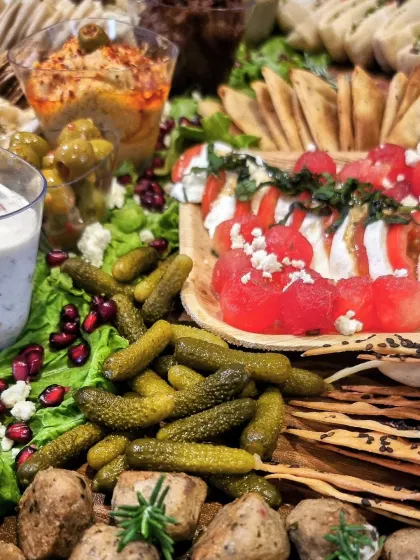 Crackers, dips and little savoury bites surround fruit and vegetables on our Med non veg platter, with flowers between the rows.