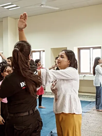 A female participant practices a blocking technique during a workshop. This is a fundamental skill for deflecting an incoming strike and creating an opening for a counter-attack.