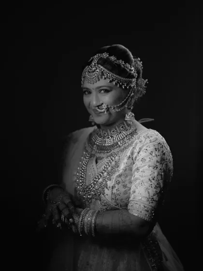 A classic, smiling bridal portrait in black and white, highlighting her intricate jewelry and happy expression.
