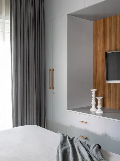 The wardrobe and integrated TV unit in the guest bedroom, showcasing a clean design with a mix of grey and wood laminate.