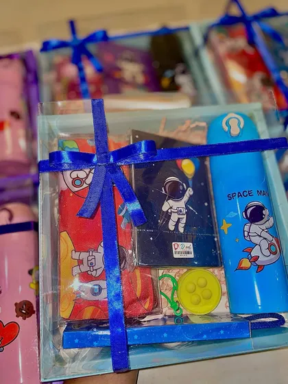 This Space-themed hamper includes a pencil pouch, diary, water bottle, pens, and erasers, all tied together with a blue ribbon.