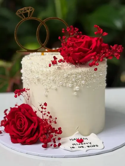 A beautiful engagement cake with red roses and baby's breath against a white pearl-dusted cake. A classic and romantic combination.