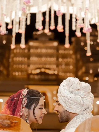Under a beautifully decorated mandap with a grand palace illuminated in the background, the couple shares an intimate glance. This frame captures the romance and scale of a destination wedding in Jaipur.