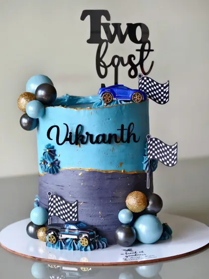 "Two Fast" and super cute. This car-themed cake was for a second birthday, featuring two tones of blue buttercream, race cars, and checkered flags.