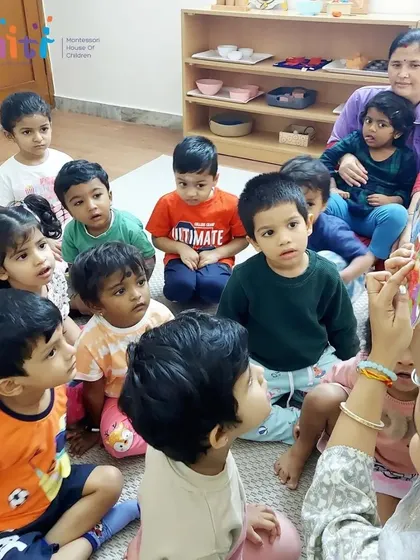 A group of toddlers is completely absorbed in a storybook about Lord Krishna. Reading together fosters a love for books and shared learning.