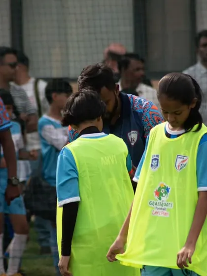 Players getting ready on the sidelines, listening to the coach and preparing to enter the game.