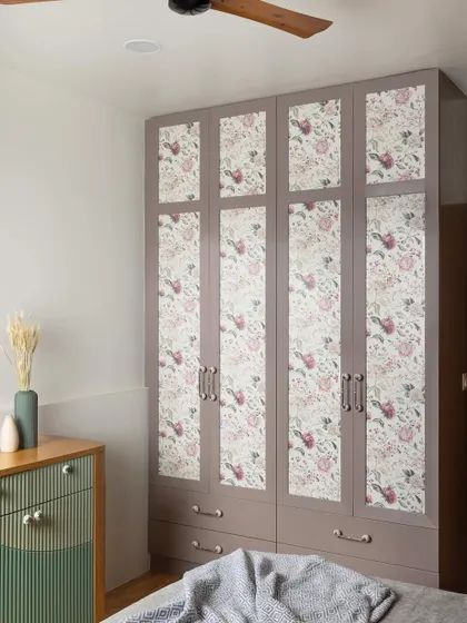 This wardrobe features fabric-sandwiched glass shutters with a floral pattern that complements the room's color palette. It adds subtle texture and vibrancy to the space.