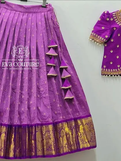 Another view of the elegant purple pattu lehenga. This angle highlights the pretty tassels on the skirt and the detailed embroidery work on the puff-sleeved blouse.