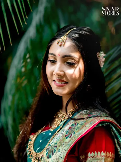 A close-up bridal portrait in a lush, green setting. The natural light filtering through the leaves creates a beautiful, soft effect.