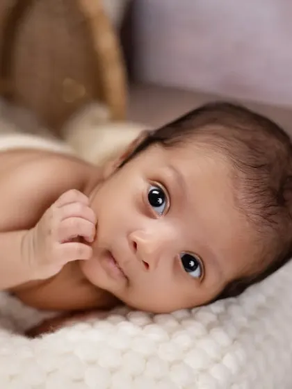 A quiet moment of contemplation for this little one. This close-up portrait on a soft white blanket captures the beautiful, soulful eyes of a newborn.