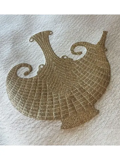 The 'Carafe' fabric is an opulent textile featuring abstract forms inspired by Indian Dokra metal casting. The gold embroidery on a cream base is perfect for creating decadent, art-inspired interiors.