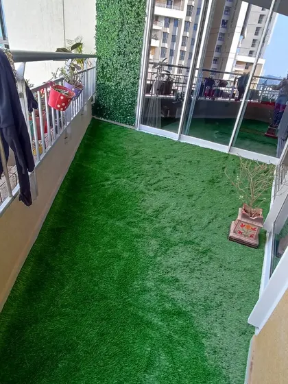 A high-angle view of a completed balcony project featuring an artificial grass floor and a green wall. This setup is perfect for city living, providing a clean and green space without the need for maintenance.