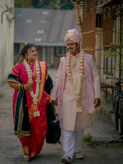 A candid shot of the couple walking hand-in-hand through a narrow lane, sharing a happy glance, a slice of real life amidst the wedding celebrations.