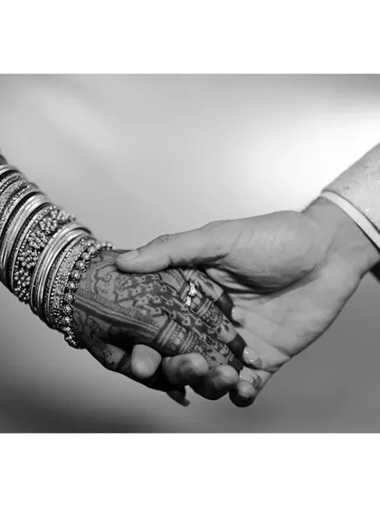 A timeless black and white shot capturing the moment a couple holds hands, showcasing the bride's intricate mehendi. This highlights how the henna becomes a part of your celebration's most cherished memories.