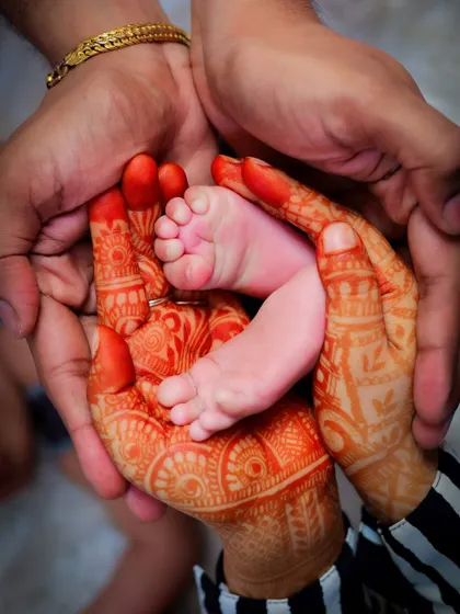 The contrast between the mother's intricate henna-adorned hands and her baby's tiny, perfect feet is just beautiful. This photo blends cultural tradition with the universal love for a new child.